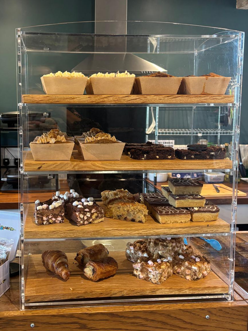 Display case with various pastries and baked goods on a wooden shelf.